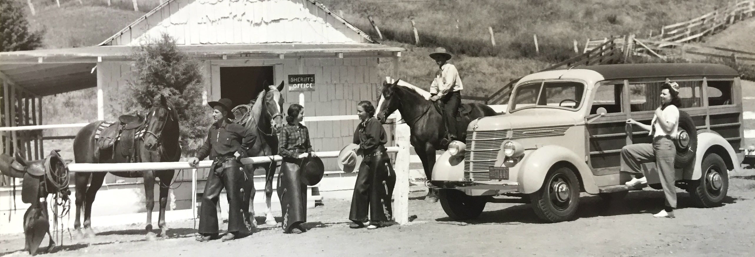 Western Scene of Cowboys, Ranch Hands and Riders gathering around an old barn, an old Woodie Wagon and Horses