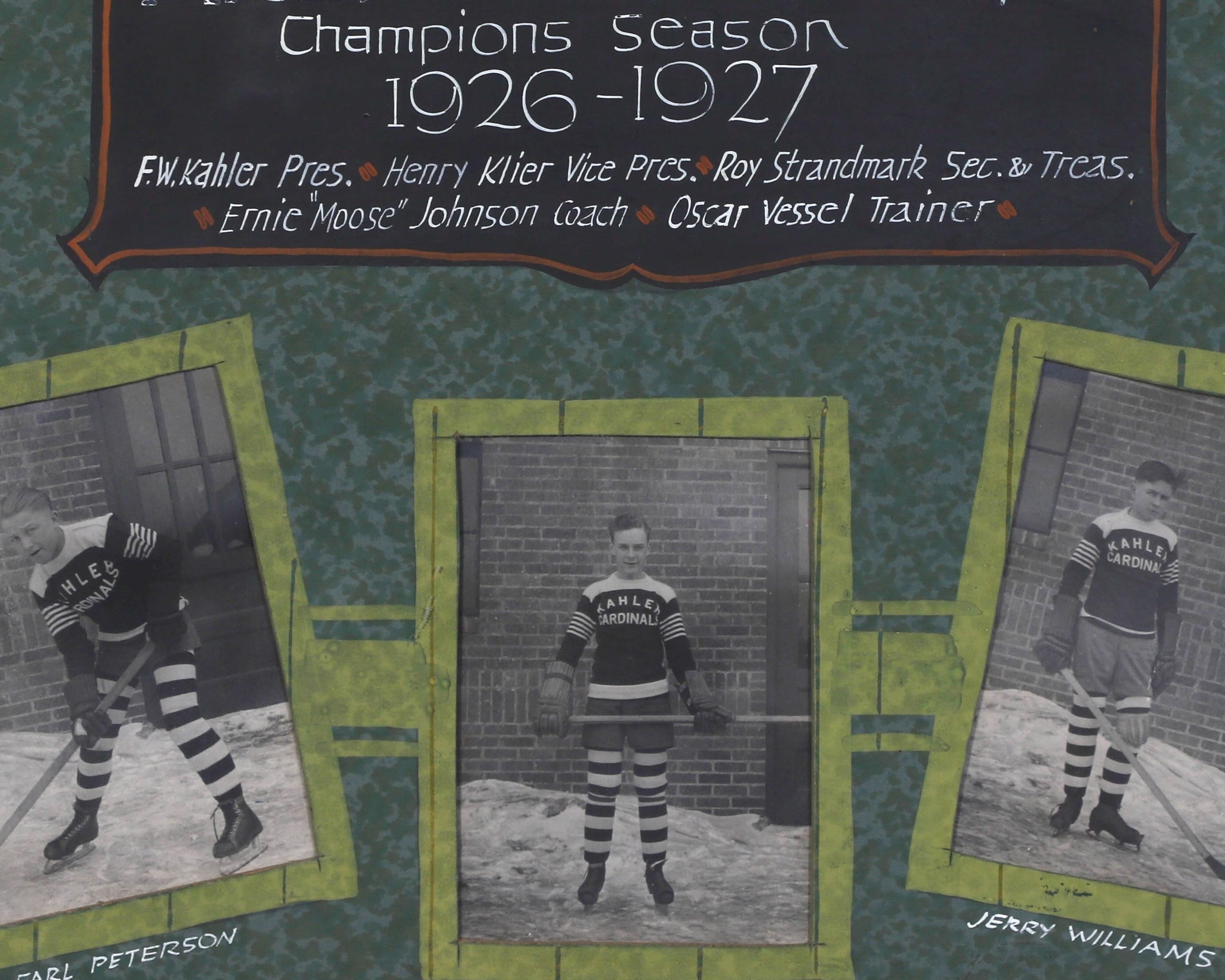 Detail of the framed vintage photo collage of the Arena Juvenile hockey team from the 1926-1927 season. The collage features individual black-and-white photographs of twelve players in their uniforms, arranged around a central plaque with the team’s name and season details. The frame is wooden with a green matt as background and each player’s name is displayed beneath their photo.