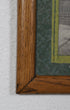 Corner of wood frame with small section of green mat and an unidentifiable portion of one photo showing