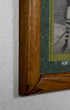 Corner of wood frame with small section of green mat and an unidentifiable portion of one photo showing.