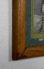 Corner of wood frame with small section of green mat and an unidentifiable portion of one photo showing