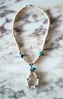 Vintage 1960s necklace with shell heishi beads, turquoise nuggets, and loop pendant on marble background.