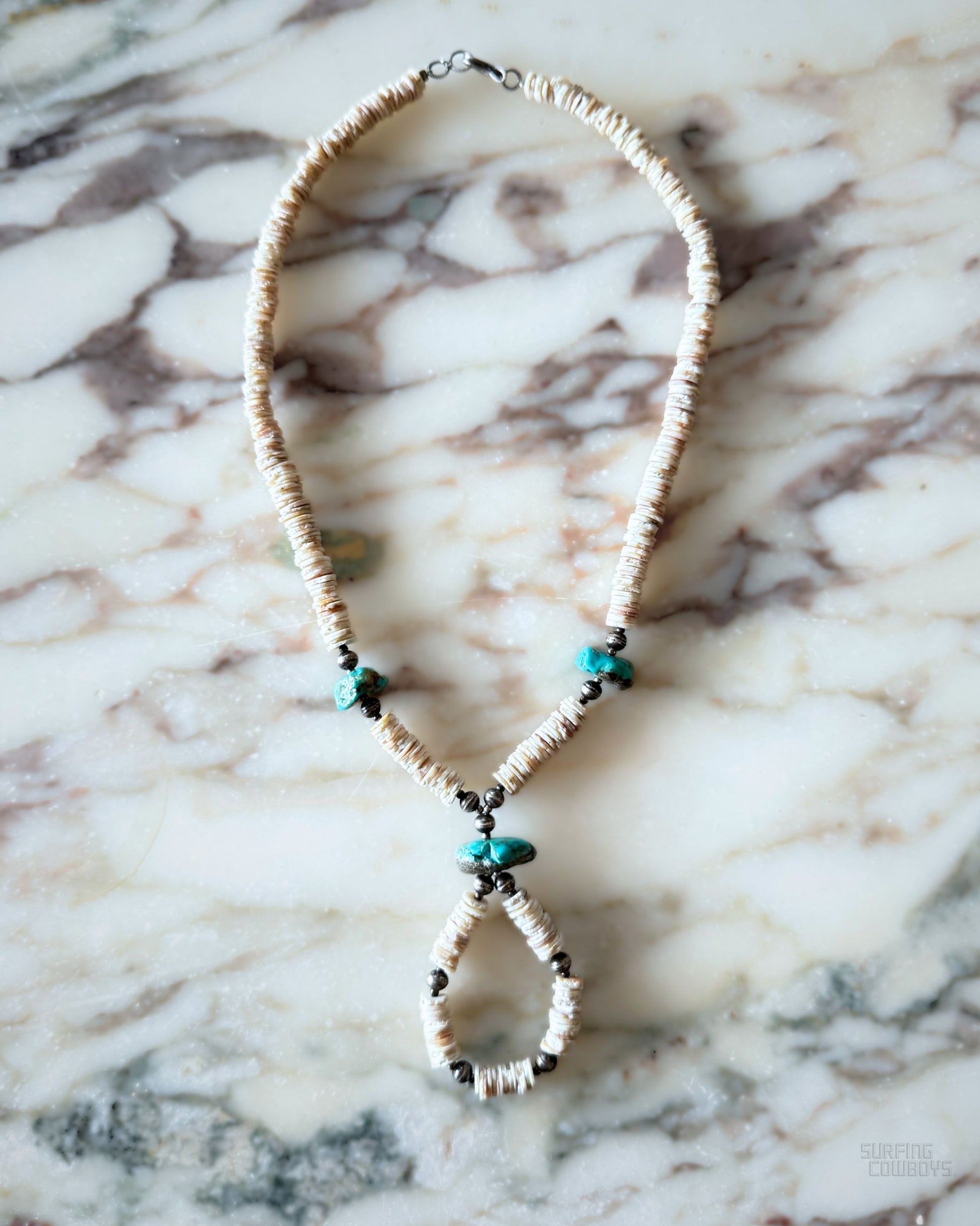 Vintage 1960s necklace with shell heishi beads, turquoise nuggets, and loop pendant on marble background.
