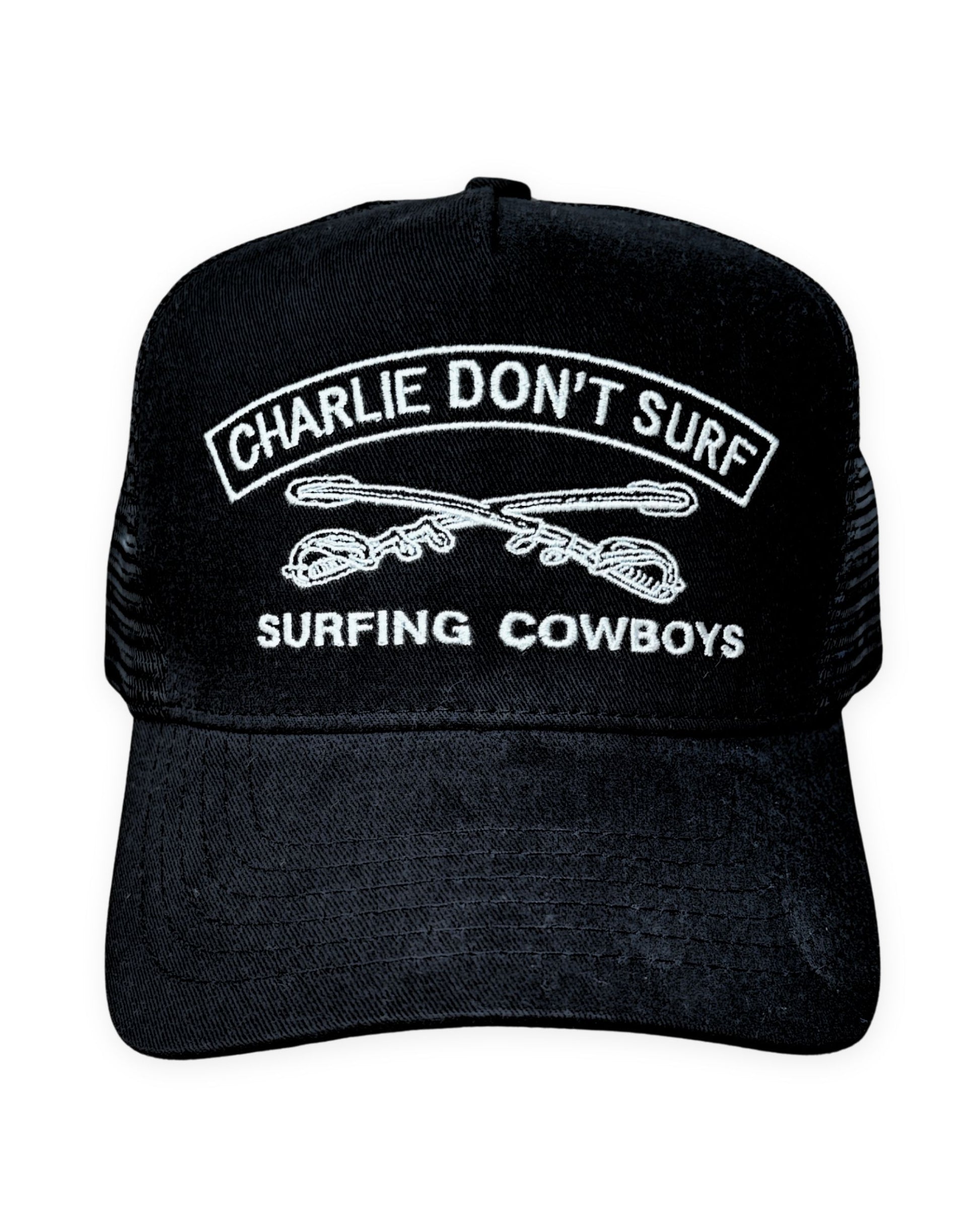 Black cap with 'Charlie Don't Surf' and 'Surfing Cowboys' text on a white background