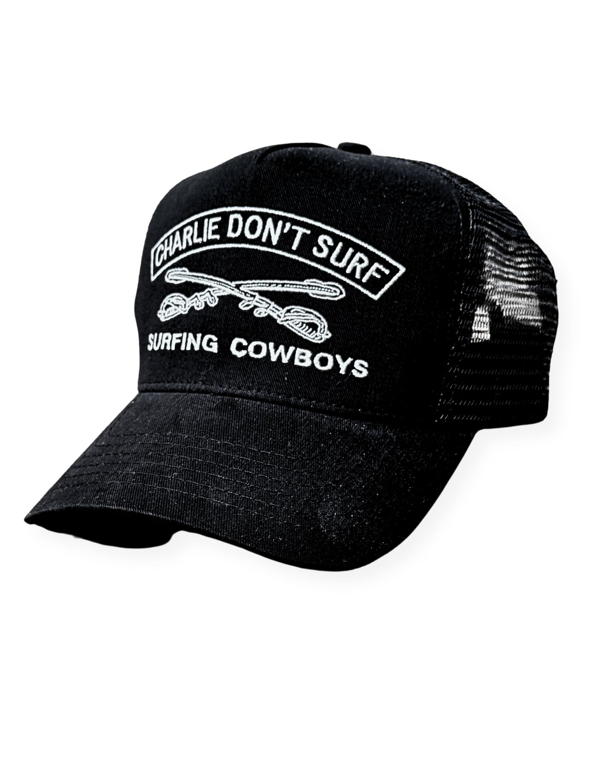 Black cap with 'Charlie Don't Surf' and 'Surfing Cowboys' text on a white background