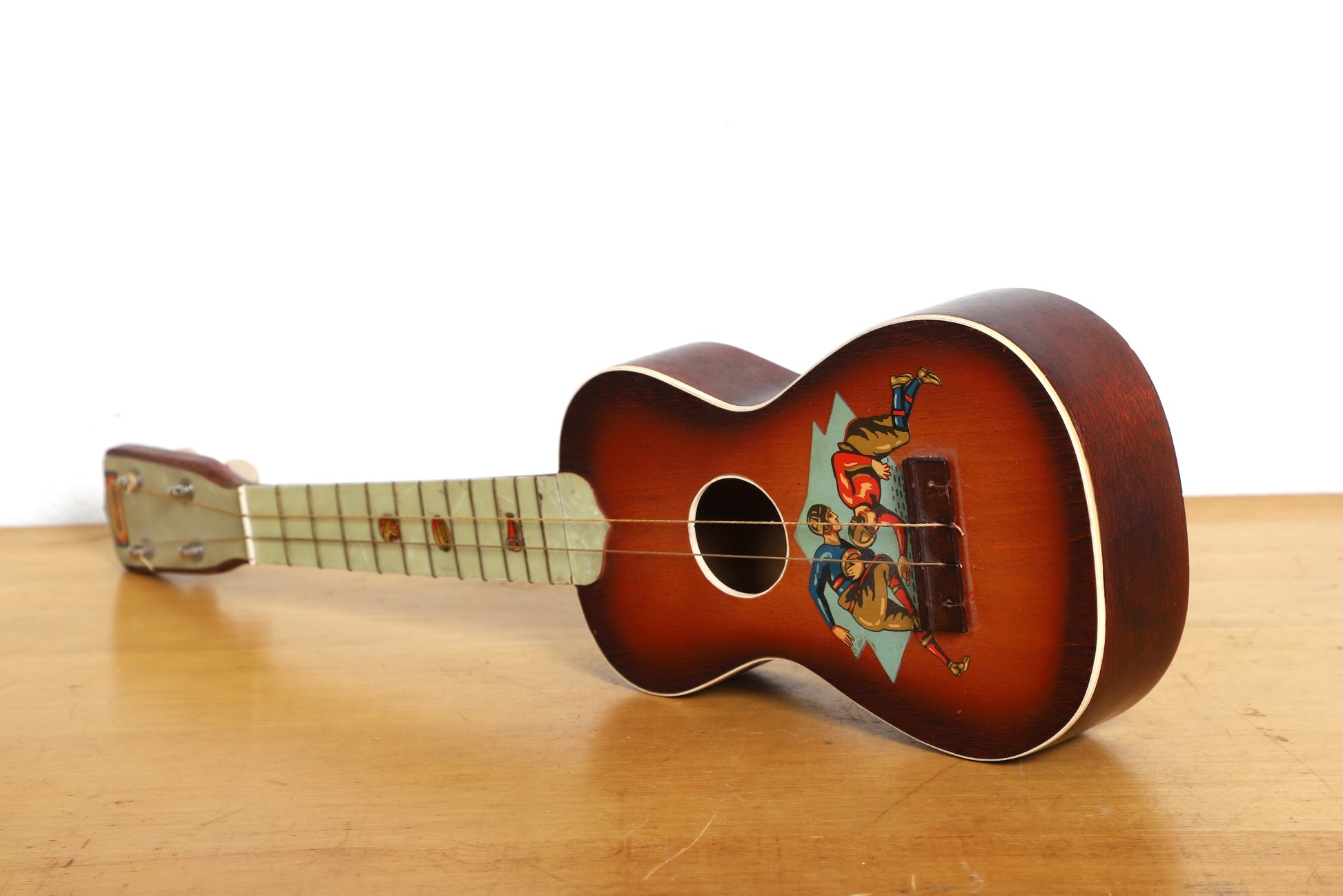  Vintage soprano ukulele with 1920s football scene graphic on body.