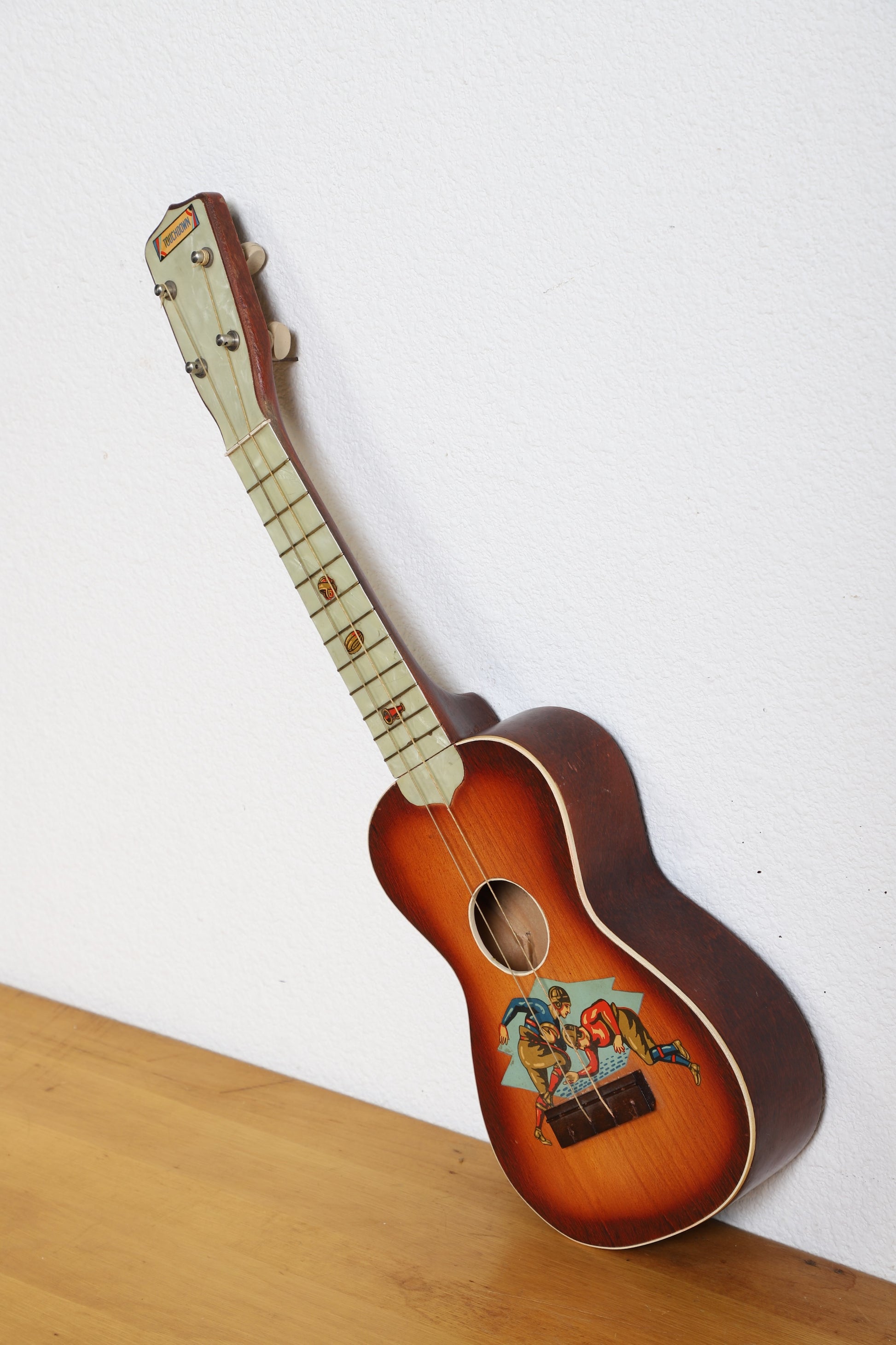 1920s Touchdown ukulele with football player graphic and faux pearl fretboard.