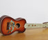  Vintage soprano ukulele with 1920s football scene graphic on body.