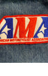 Close-up of a red, white, and blue embroidered American Motorcyclist Association patch on faded blue denim.