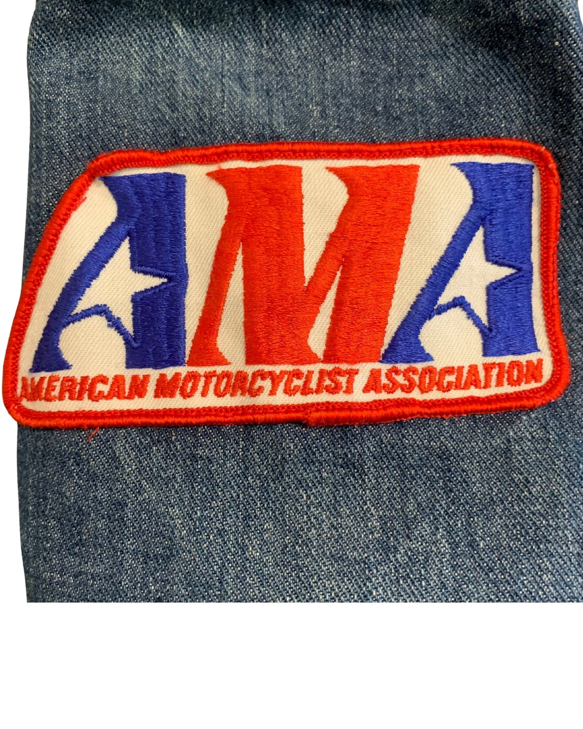 Close-up of a red, white, and blue embroidered American Motorcyclist Association patch on faded blue denim.