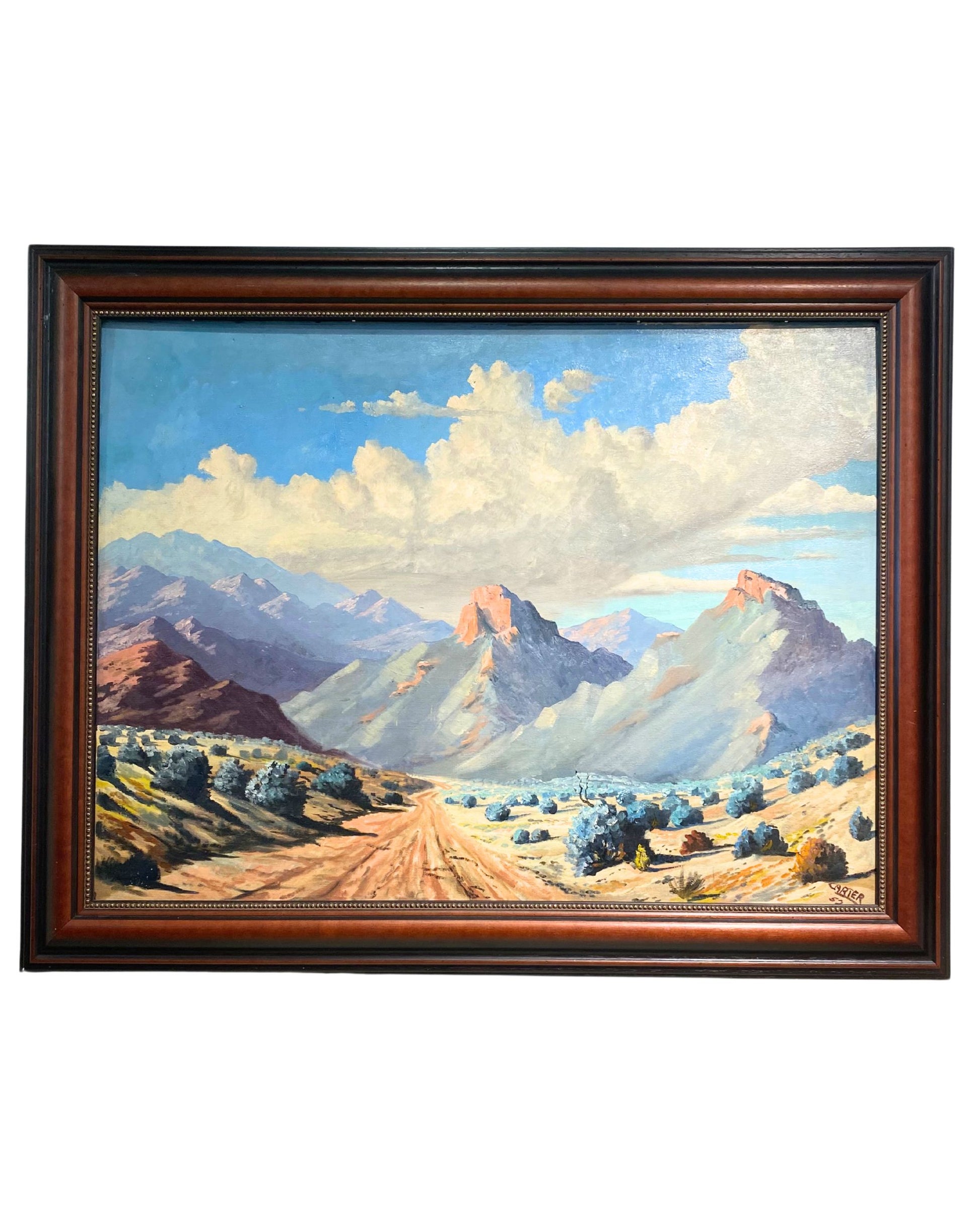 Framed painting of a mountain landscape with a dirt road and blue sky.