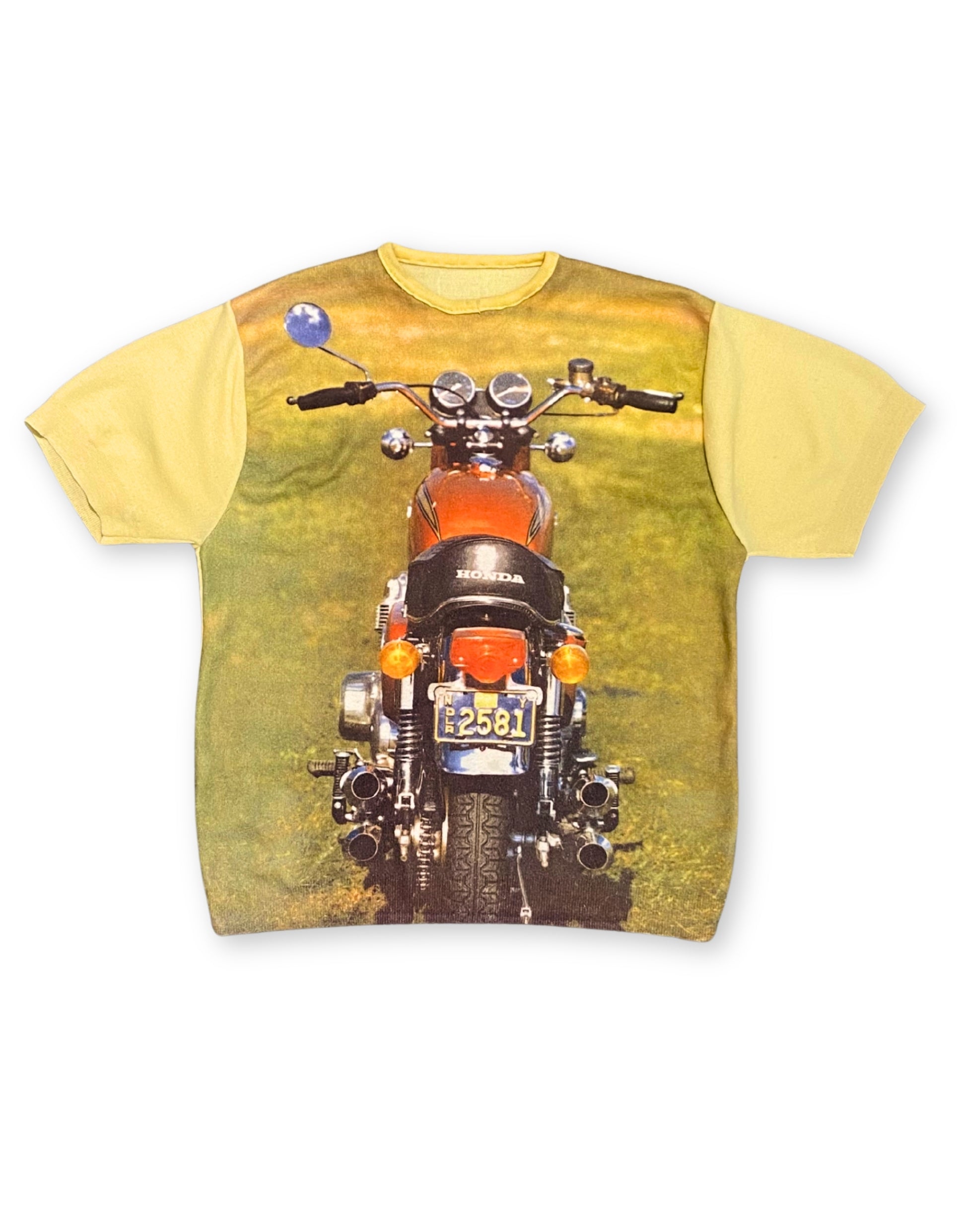 Front view of vintage 1970s yellow knit shirt with all-over Honda motorcycle photo print.