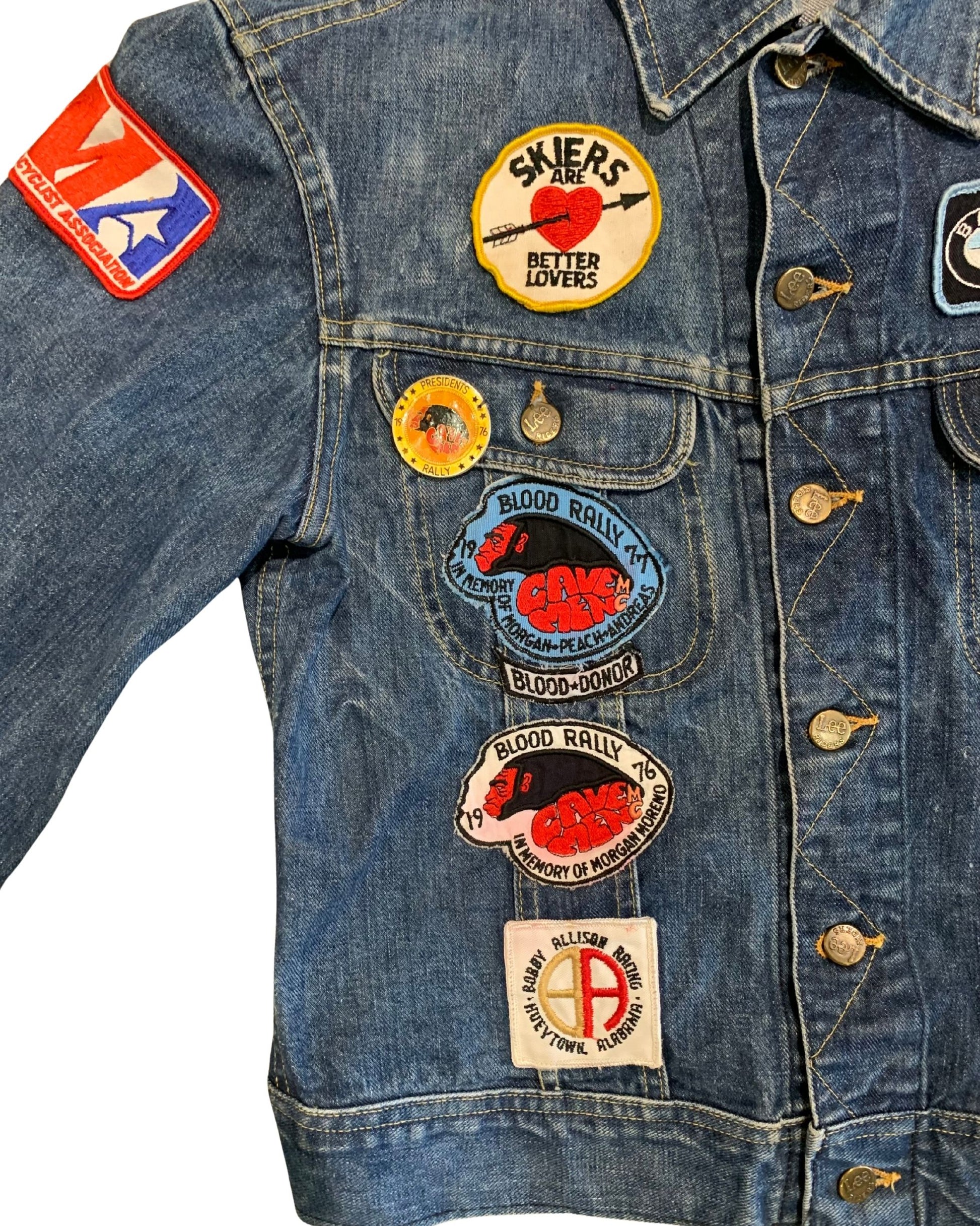 Close-up of the left front of a Lee denim jacket with “Skiers Are Better Lovers,” 1976 Blood Rally, Road Runners rally, and other vintage patches and pins.