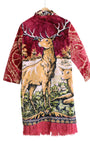 Artisan tapestry coat with stag and deer design, red velvet sleeves, and fringe hem. Handmade one-of-a-kind outerwear in vivid colors.