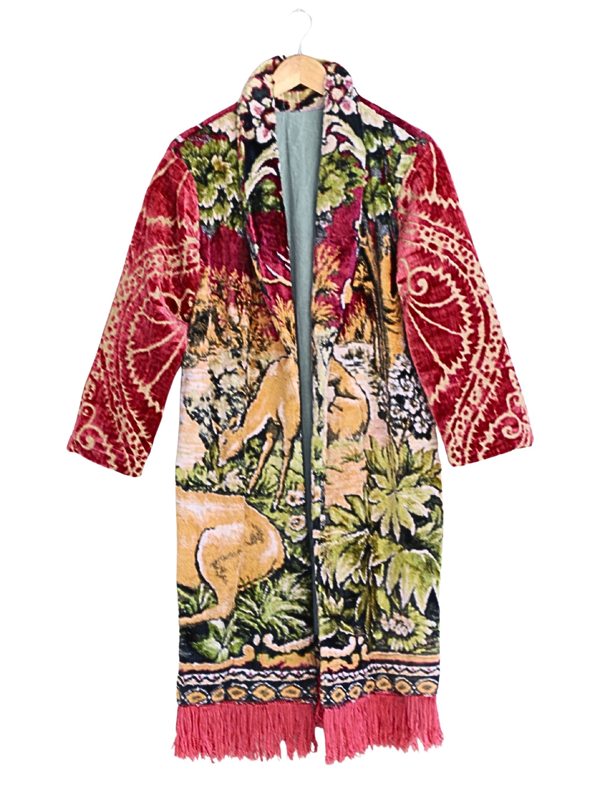 Artisan tapestry coat with stag and deer design, red velvet sleeves, and fringe hem. Handmade one-of-a-kind outerwear in vivid colors.
