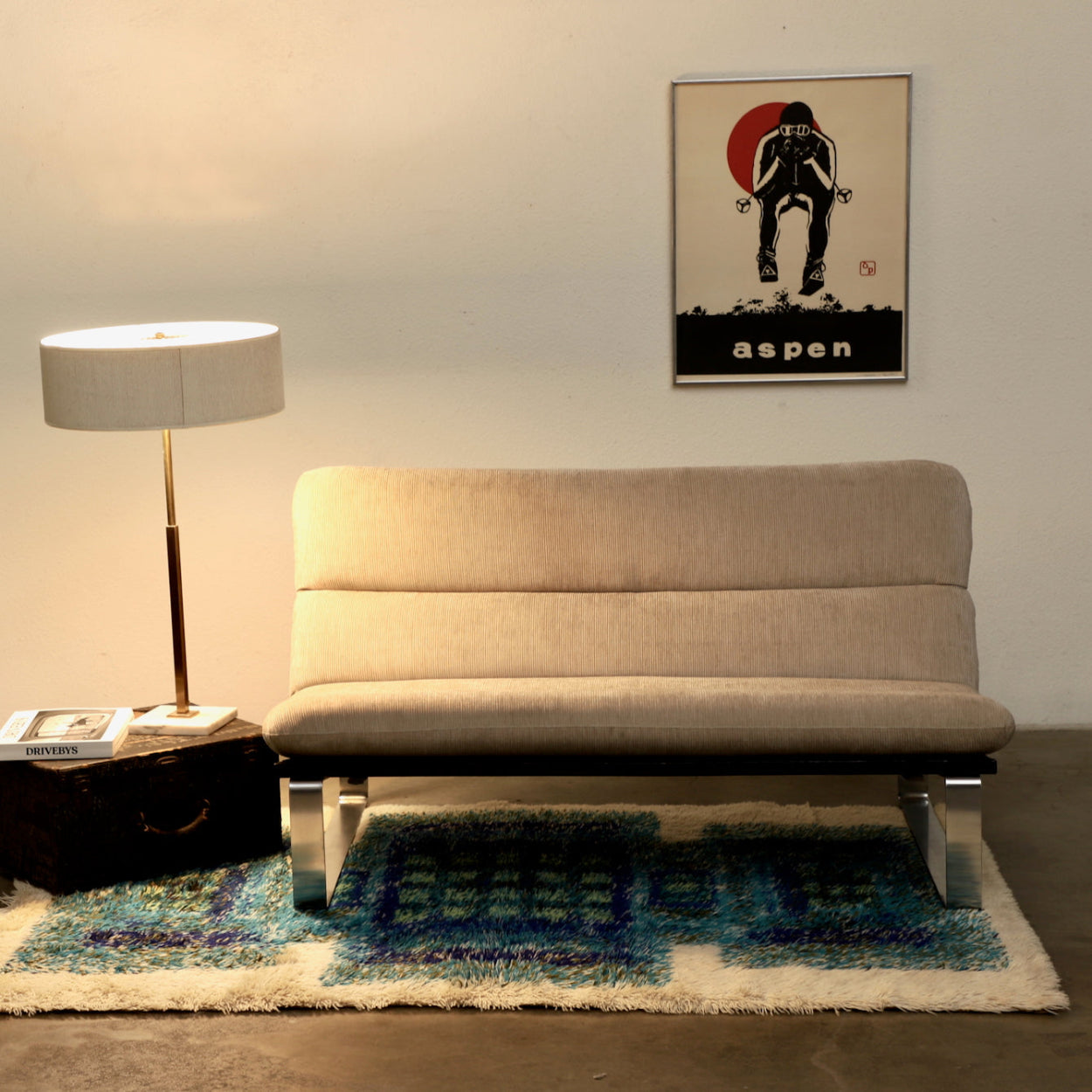 Beige sofa in a living room with a lamp, rug, and wall art.