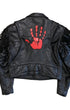 Back view of a black leather motorcycle jacket with long sleeve fringe and a large red hand patch centered on the upper back.