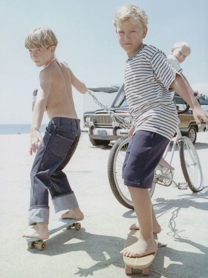 View Of 3 Boys, 2 on Skateboards and 1 On Bicycle 