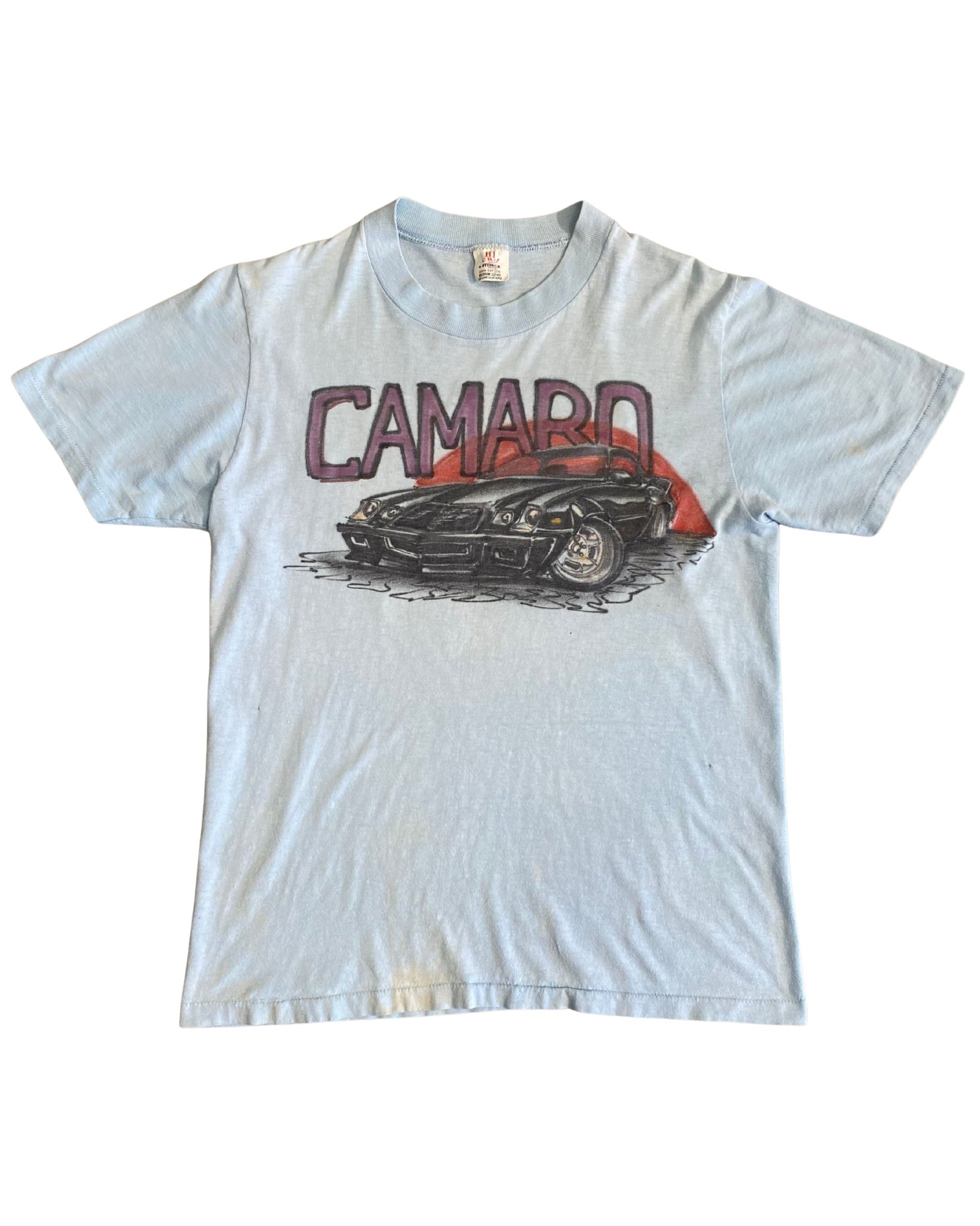 Front of light blue 1970s Camaro airbrush-style T-shirt with red sun and muscle car graphic.