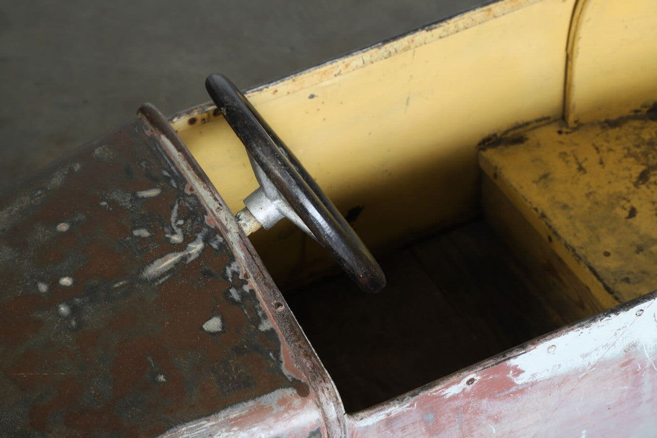 The upclose view of the steering wheel and inside of the Carnival Car Ride piece, circa 1930s.