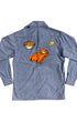 Back view of vintage 1980s chambray shirt featuring large orange sports car appliqué, steering wheel patch, and retro automotive accents.