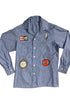 Front view of vintage 1980s chambray shirt with racing-themed patches including Champion logo, stopwatch, and spark plug.