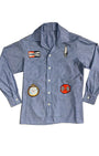 Front view of vintage 1980s chambray shirt with racing-themed patches including Champion logo, stopwatch, and spark plug.