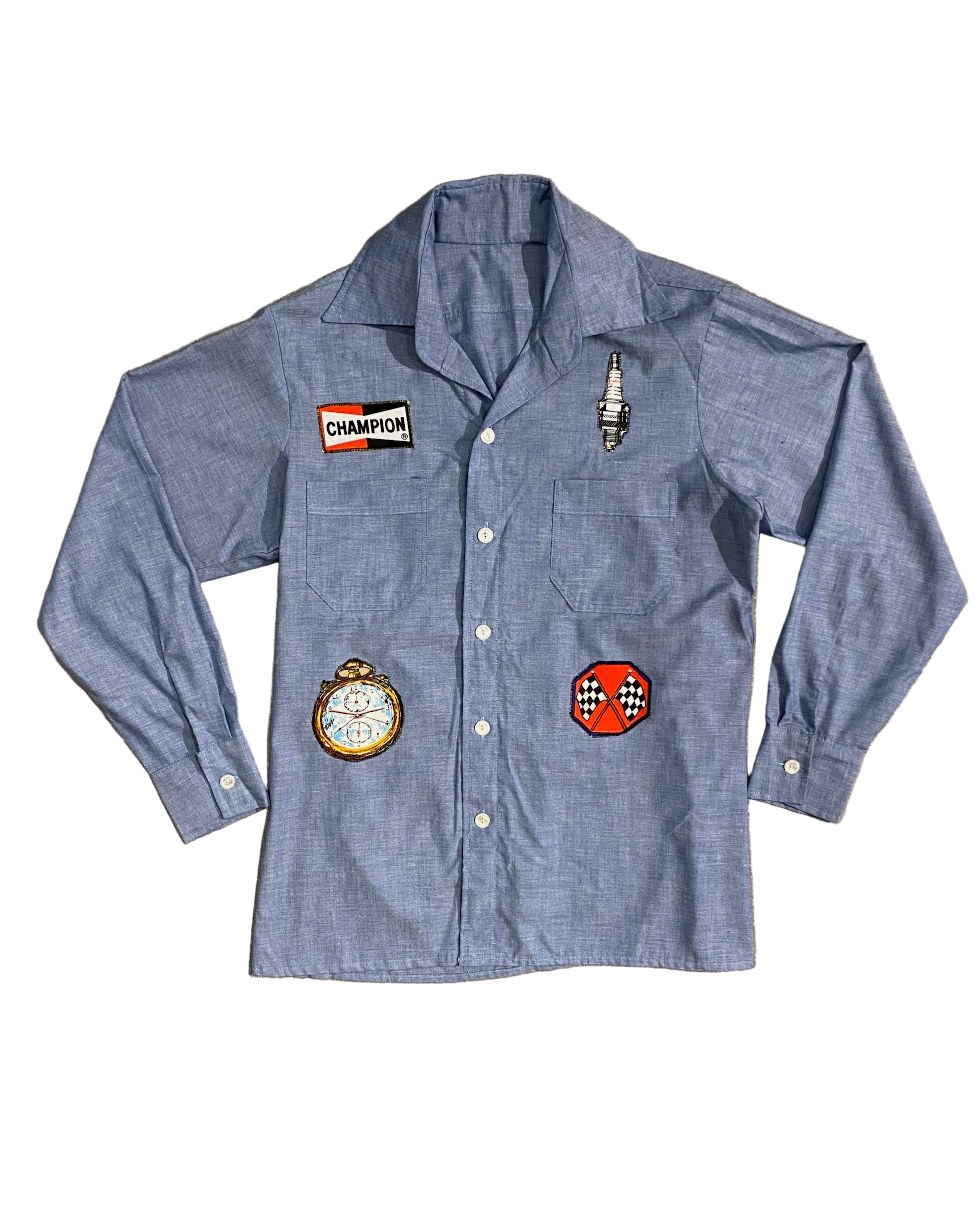 Front view of vintage 1980s chambray shirt with racing-themed patches including Champion logo, stopwatch, and spark plug.