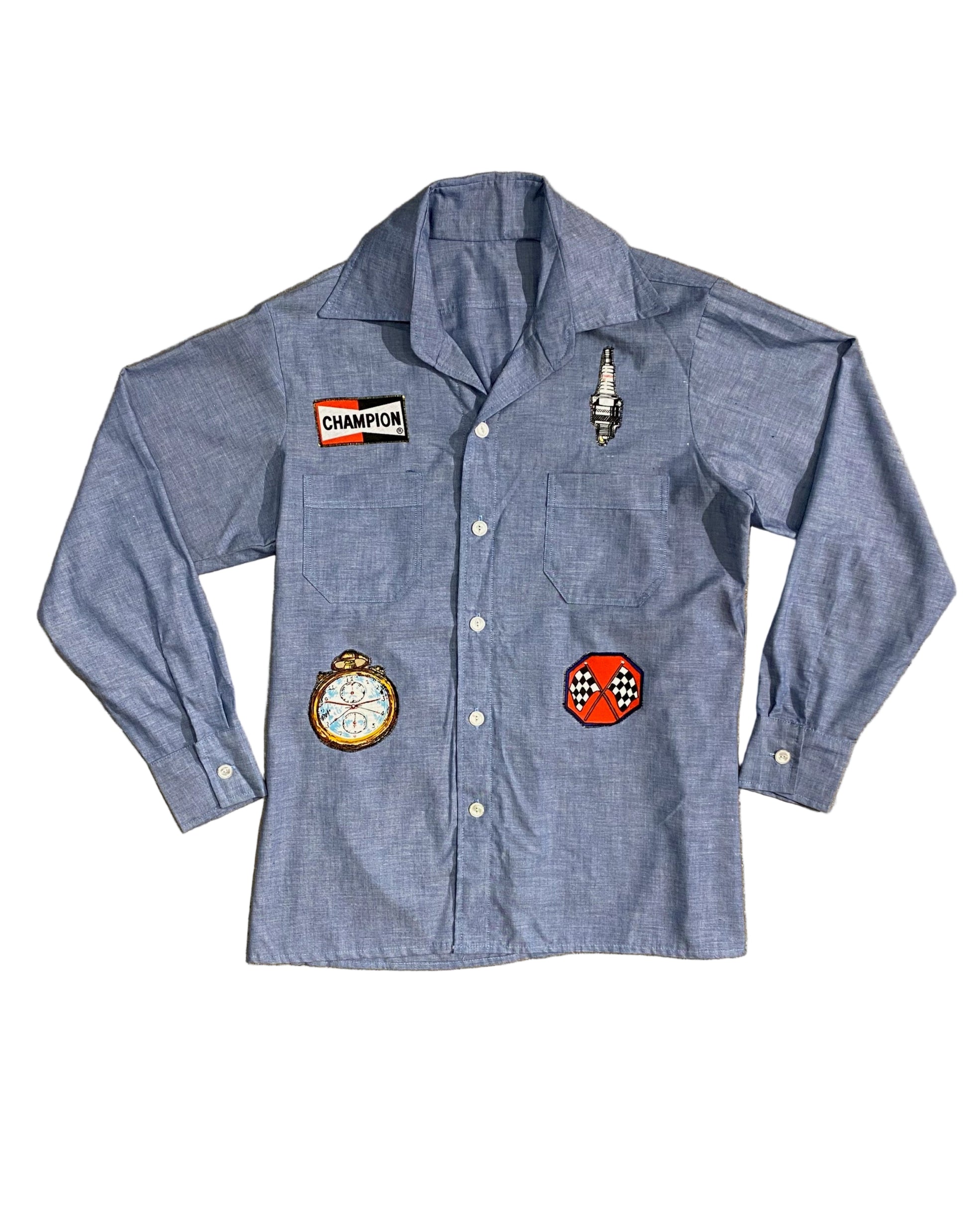 Front view of vintage 1980s chambray shirt with racing-themed patches including Champion logo, stopwatch, and spark plug.