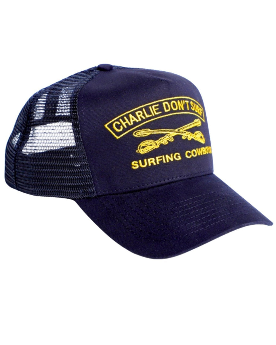 Surfing Cowboys Charlie Don’t Surf trucker hat in navy with gold embroidery, mesh back, and adjustable snapback closure.