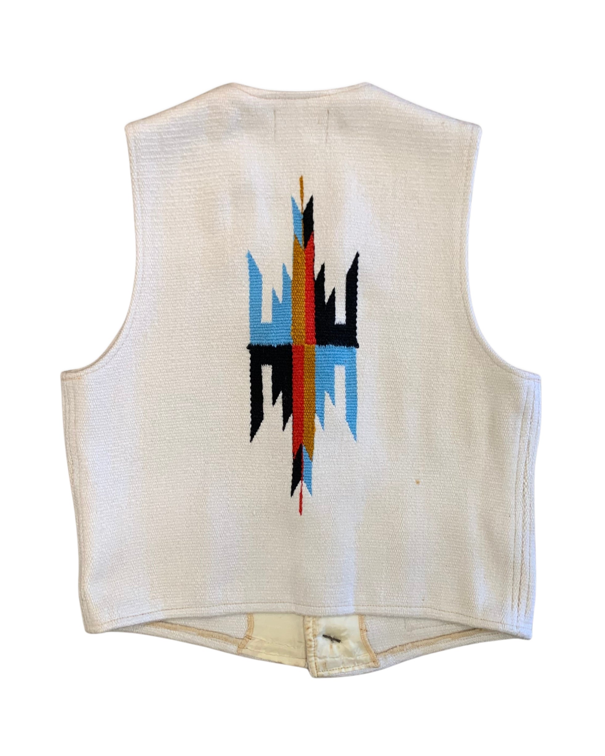 Back of a 1970s Americraft waistcoat showing a large red, blue, black, and ochre geometric motif on an off-white woven body.