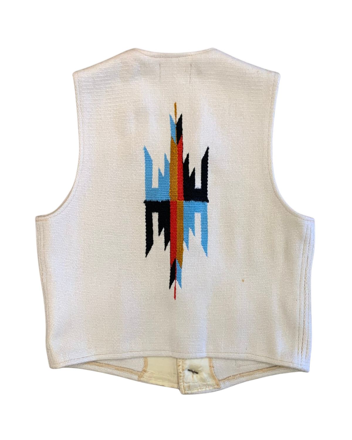 Back of a 1970s Americraft waistcoat showing a large red, blue, black, and ochre geometric motif on an off-white woven body.