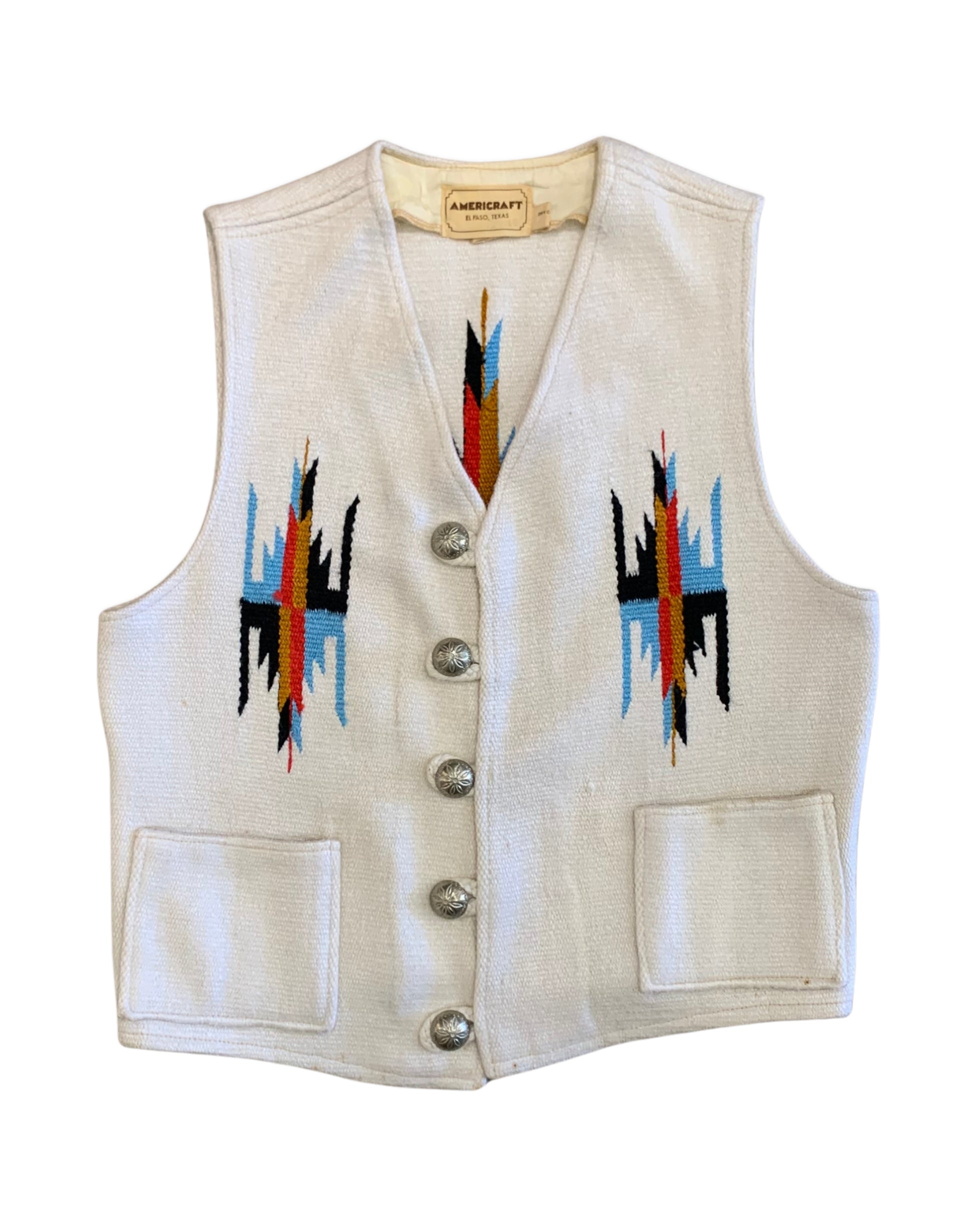 Front of a 1970s Americraft waistcoat with an off-white woven body, multicolor geometric motifs, silver-tone floral buttons, and two front pockets.