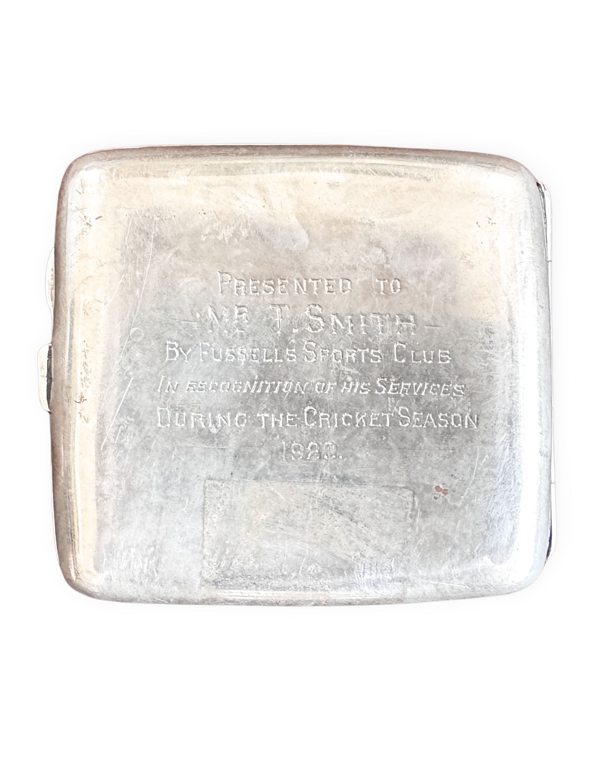 Silver cigarette case engraved with text on a white background