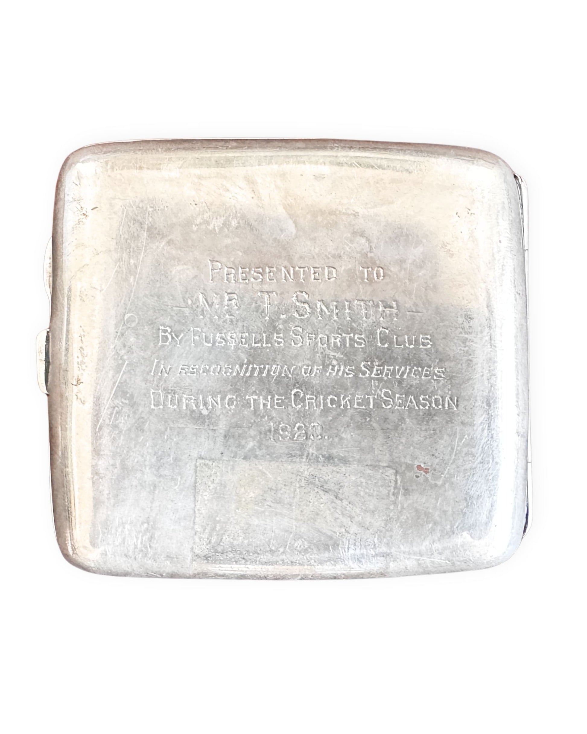 Silver cigarette case engraved with text on a white background