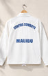 White jacket with 'Surfing Cowboys Malibu' text on a beige background