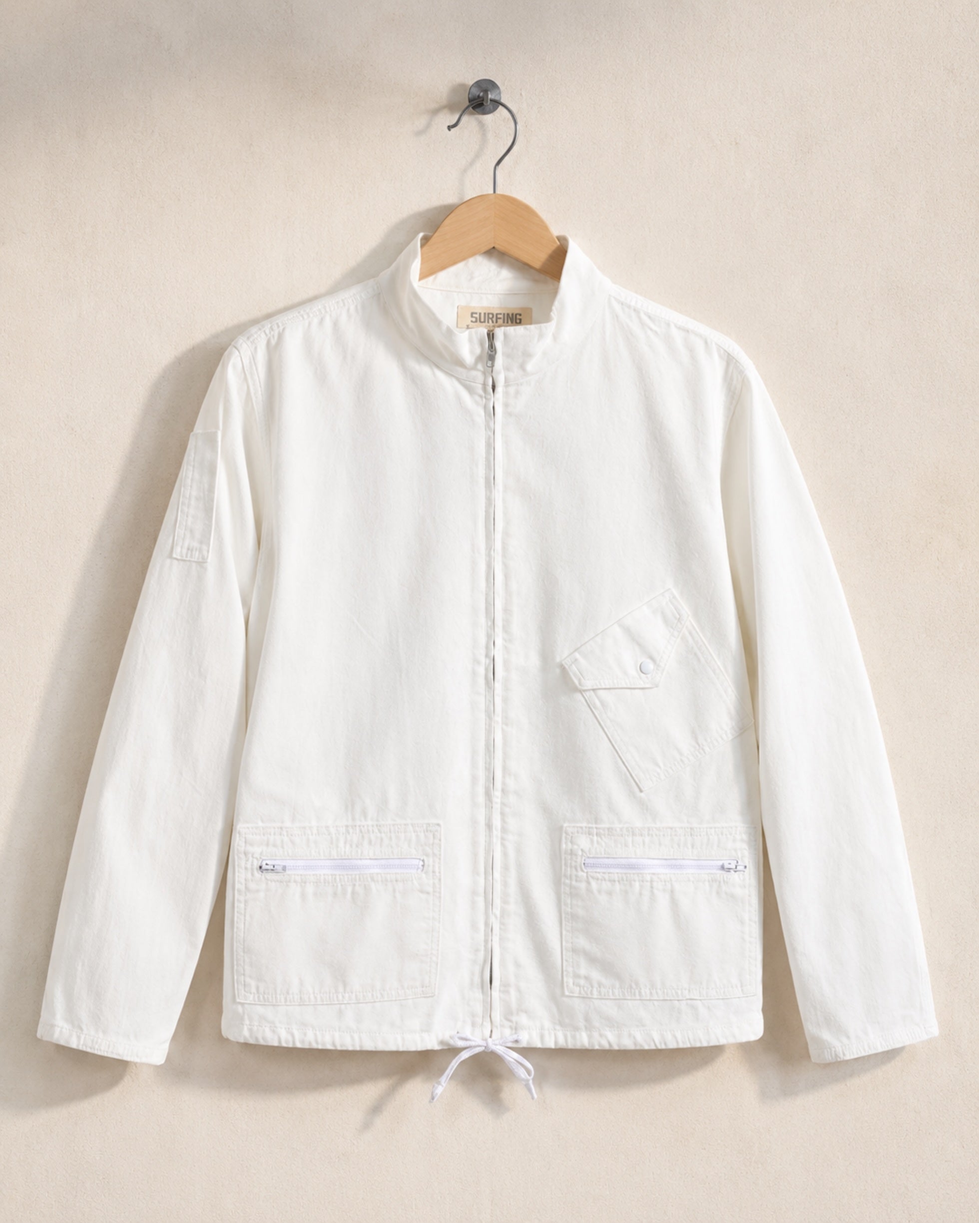 White jacket on a hanger against a beige background