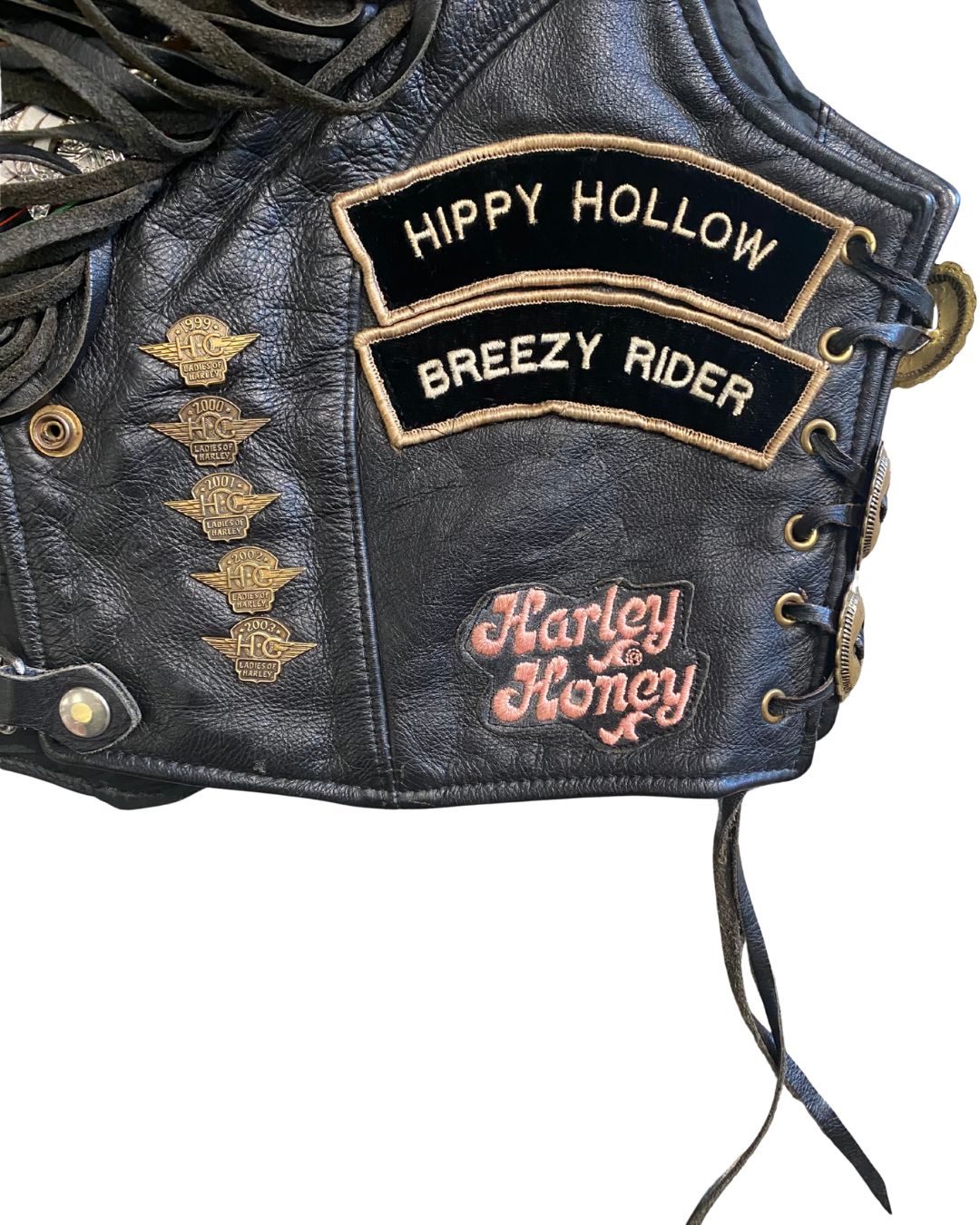 Close-up of Vintage Harley leather vest with 'Hippy Hollow Breezy Rider' and 'Harley Honey' patches.