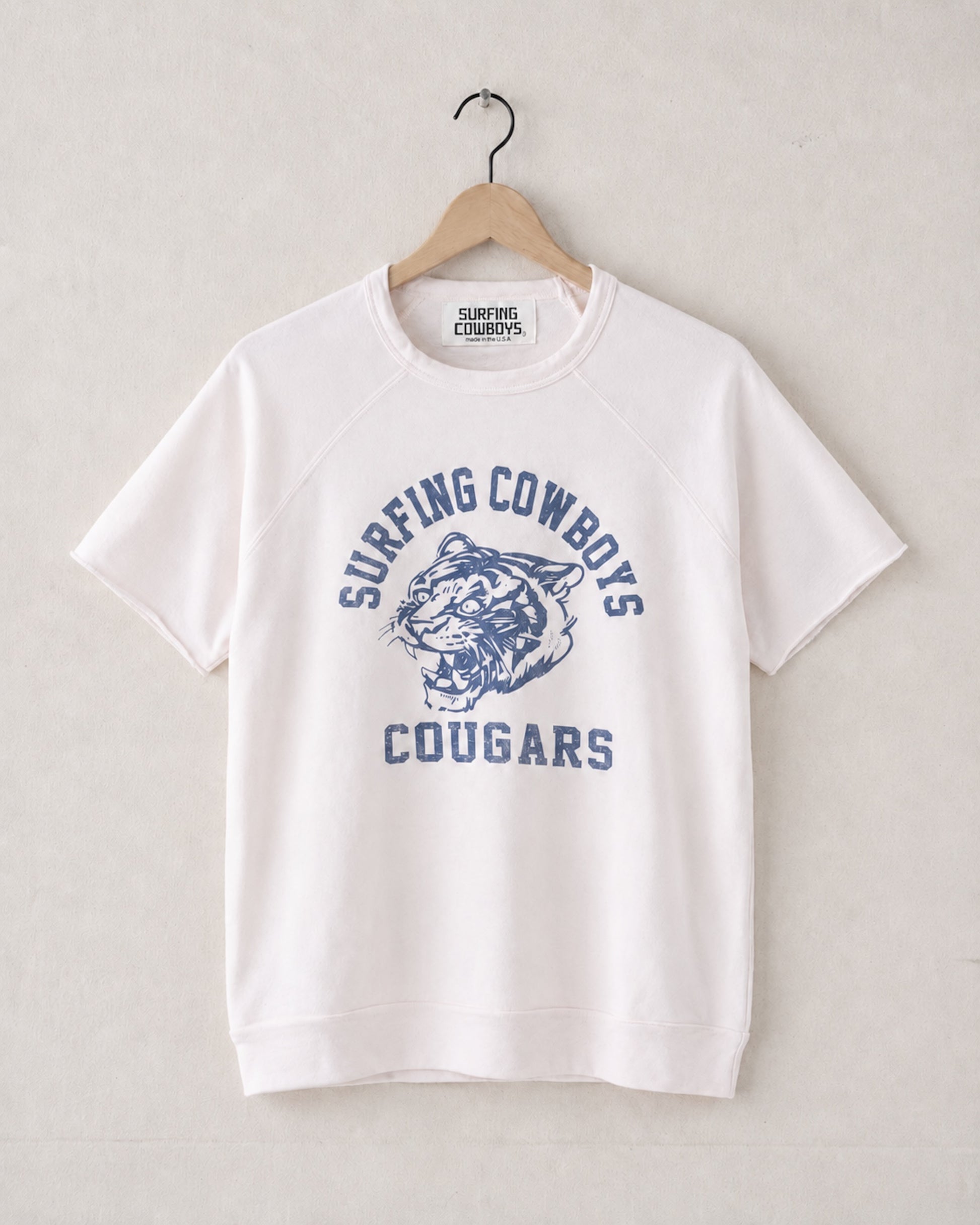 White t-shirt with blue graphic and text on a hanger against a light gray background