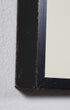 Close-up of a black picture frame corner on a textured white surface