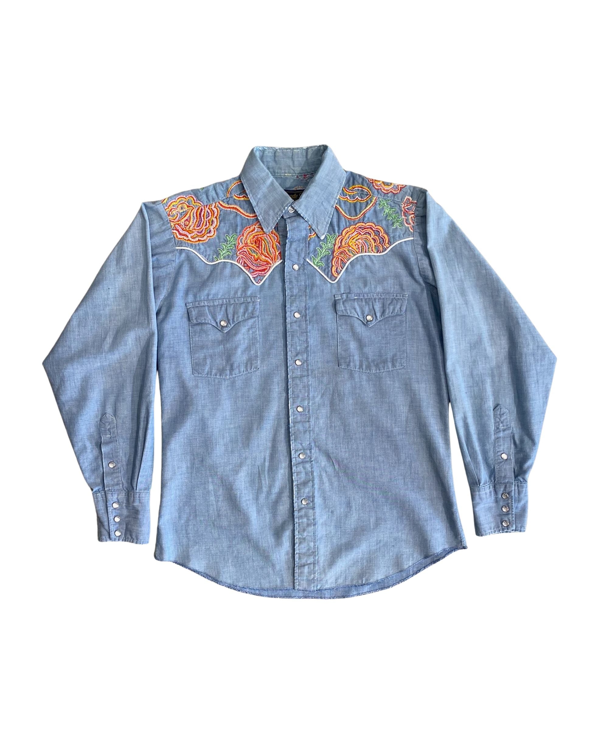Front view of 1970s snap button denim shirt with vibrant floral embroidery.