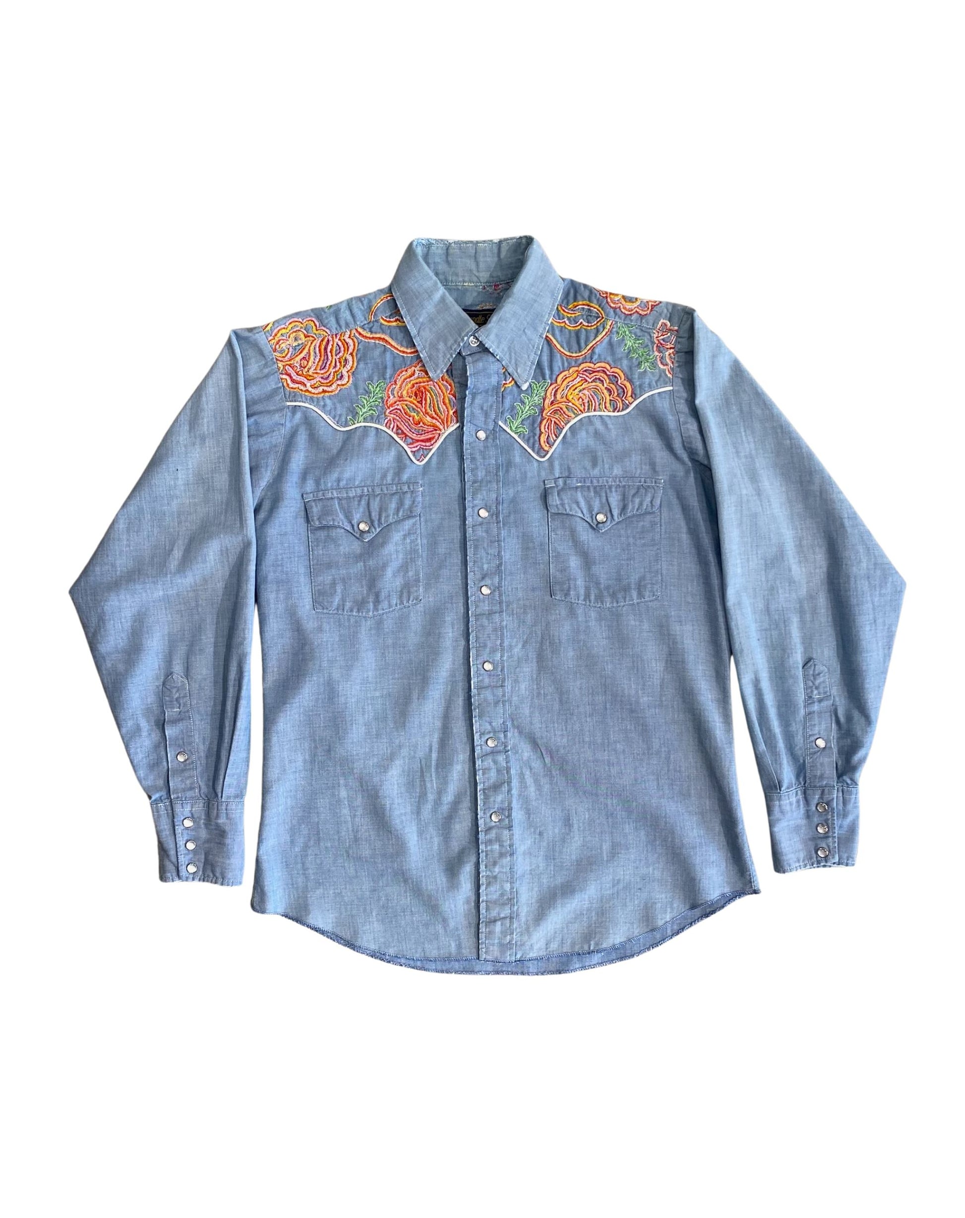 Front view of 1970s snap button denim shirt with vibrant floral embroidery.