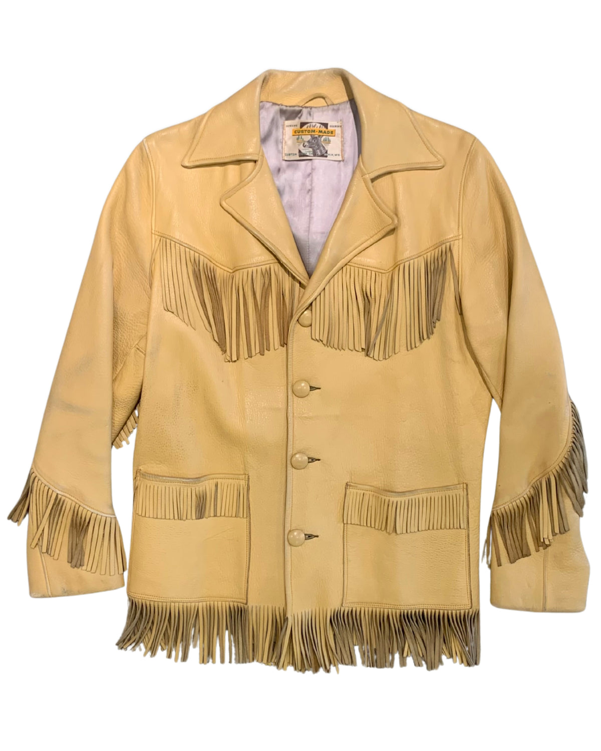 Front view of a butter tan deerskin jacket with fringe across the chest, sleeves, pockets, and hem.
