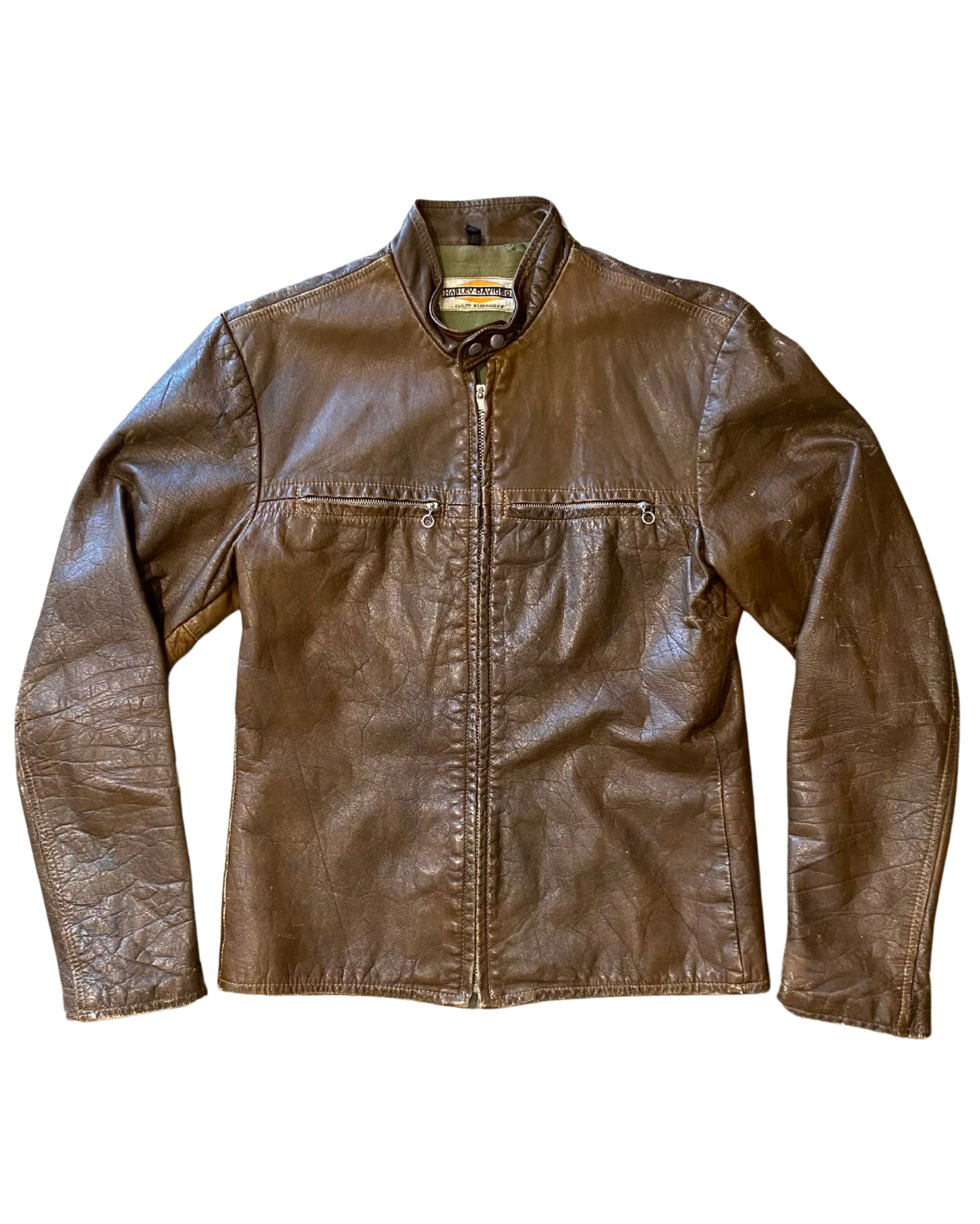 Harley-Davidson brown leather café racer jacket with a short stand collar, zippered chest pockets, and zippered cuffs. The jacket displays natural creasing and a rich patina.