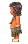  Side view of 1920s mechanical hula girl doll with grass skirt, painted composition face, and wind-up movement.