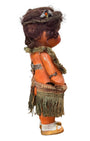 Side iew of 1920s mechanical hula girl doll with grass skirt, painted composition face, and wind-up movement.