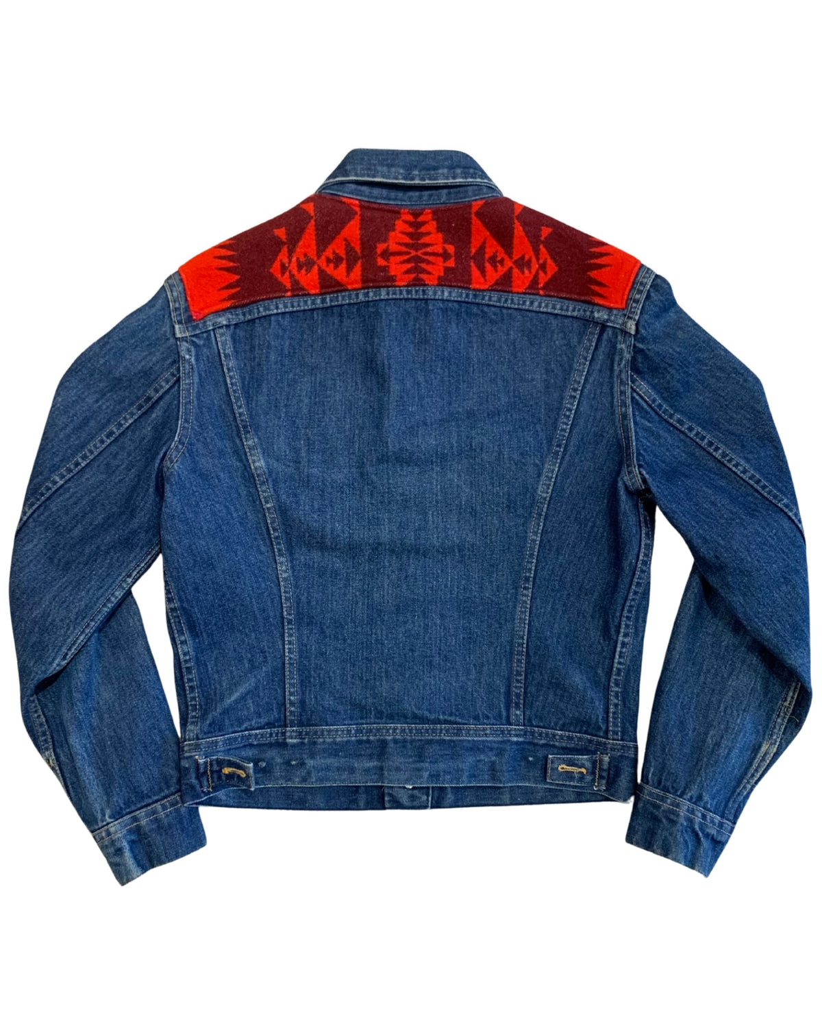 Back view of a vintage 1970s Lee denim jacket highlighting a red and rust geometric patterned wool panel across the back shoulders.