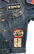Close-up of the right front of a Lee denim jacket with a BMW patch, American flag patch, Elefantentreffen Nürburgring patch, and 1976 Road Runners rally patch.