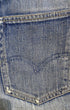 Close-up of a worn Levi’s back pocket with faded arcuate stitching, frayed corners, and a red Big E tab.