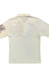 Back view of a cream Lightning Bolt short-sleeve polo with a plain body and floral artwork visible on one sleeve.